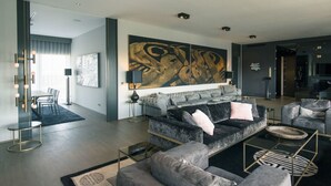 Ein modernes Wohnzimmer mit einem großen abstrakten Gemälde, einer grauen Sofagarnitur und einem Glastisch.