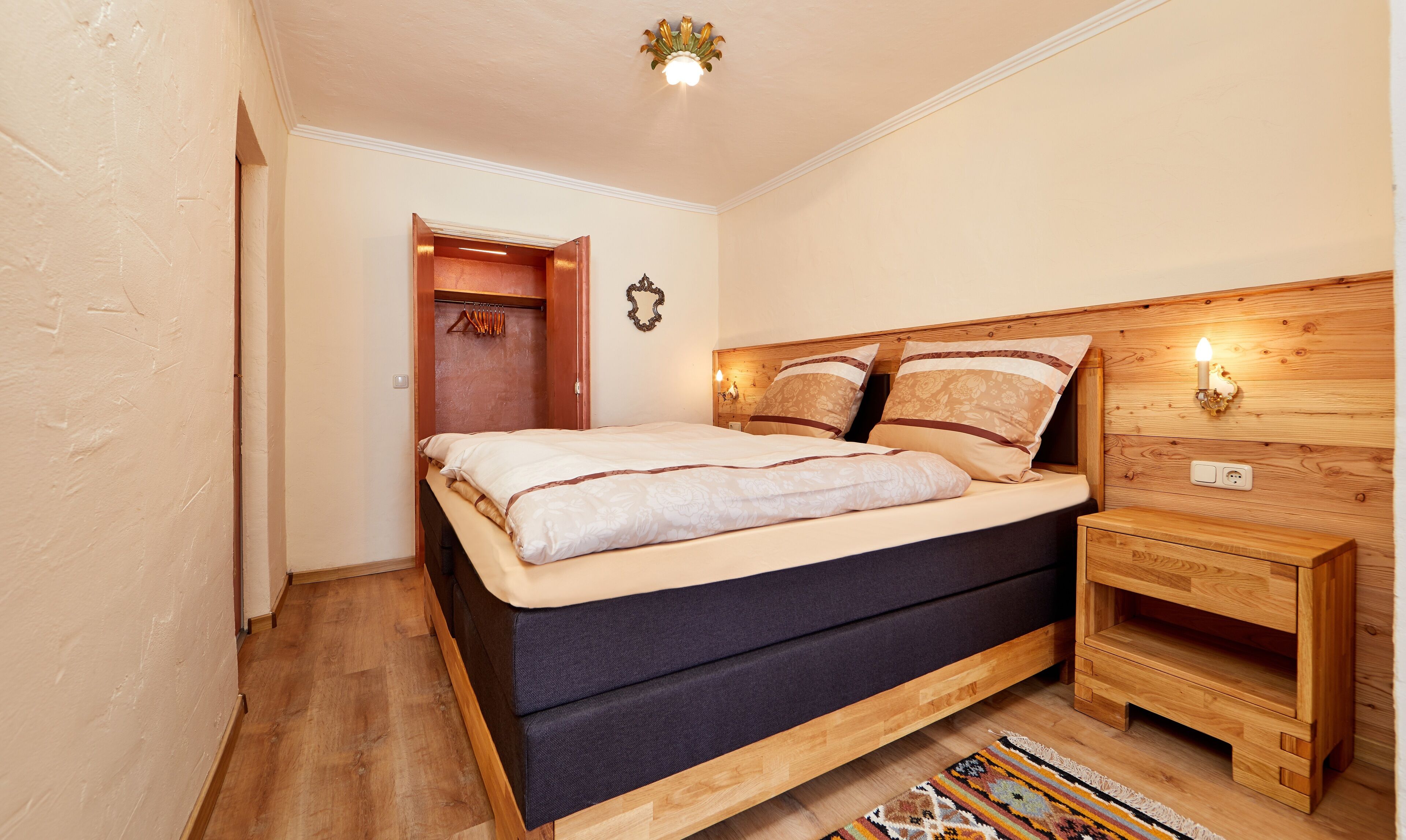 Un dormitorio con una cama de madera, mesitas de noche y un tapete estampado.