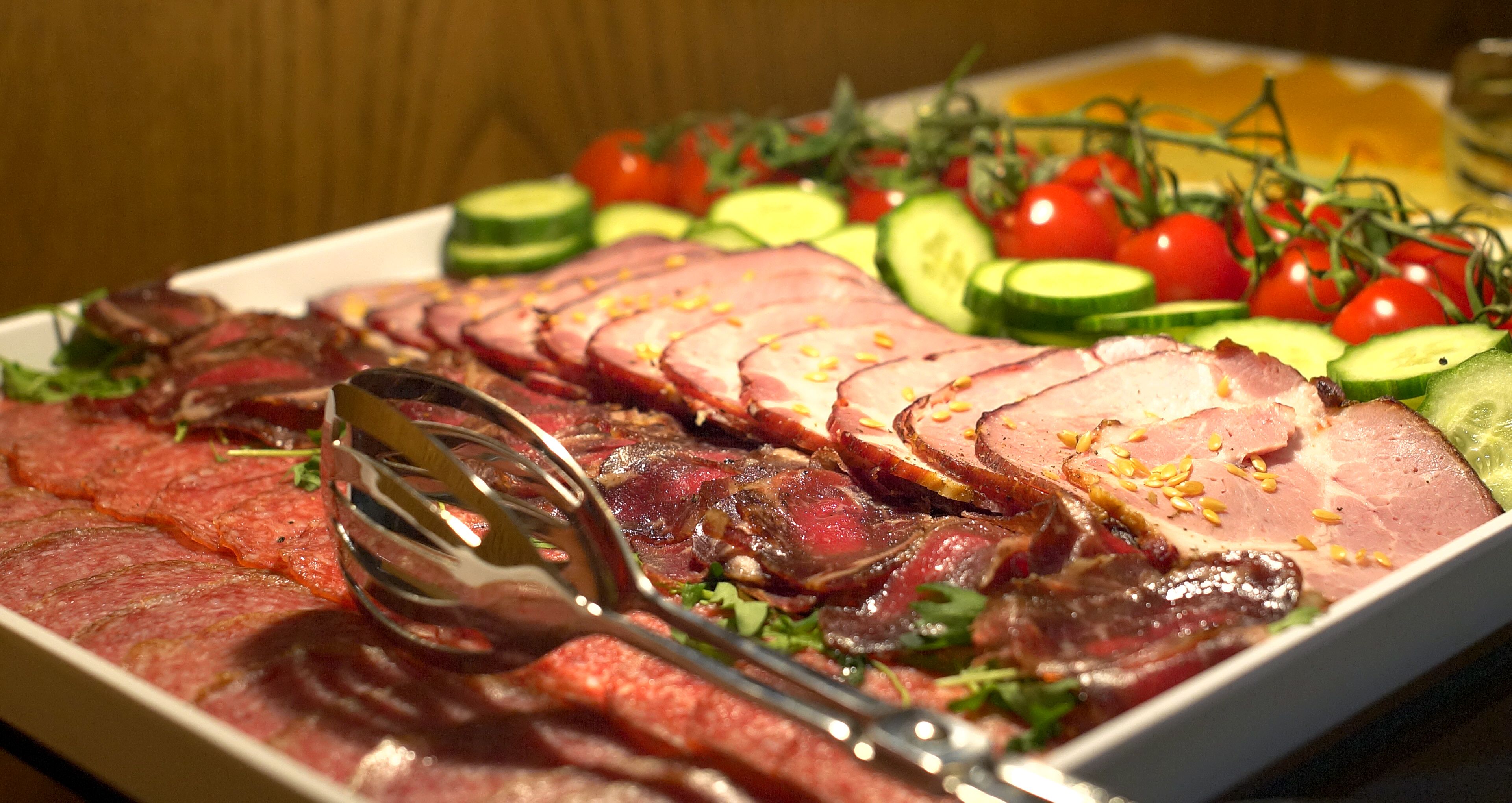 Una bandeja con carnes cortadas y verduras frescas.
