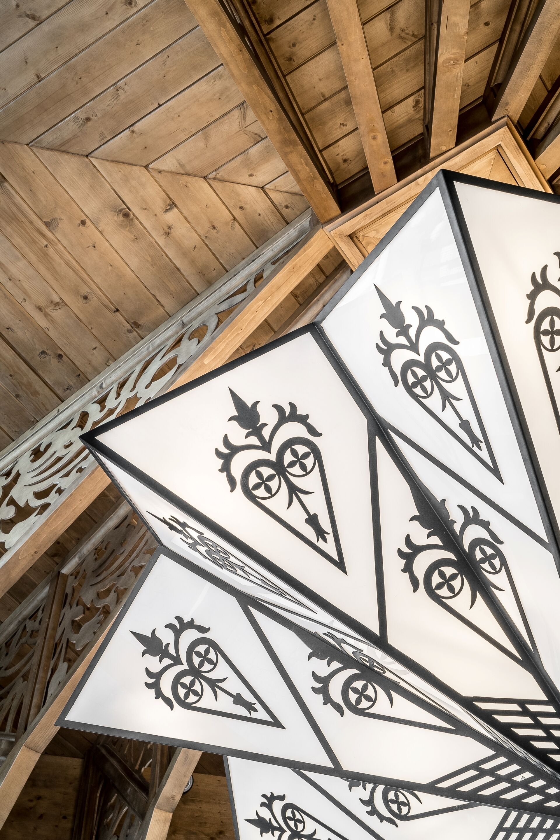 A ceiling with wooden beams and decorative metalwork.