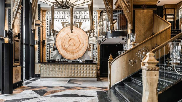 A grand staircase with a wooden handrail and a geometric patterned floor.