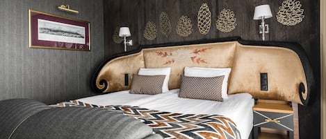 A modern hotel room with a large bed, a side table, and decorative wall art.