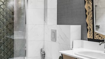 Un baño moderno con cabina de ducha de vidrio, un inodoro blanco y un lavamanos con espejo.
