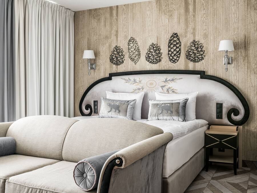 Ein modernes Schlafzimmer mit einem großen Bett, einer Couch und dekorativer Wandgestaltung.