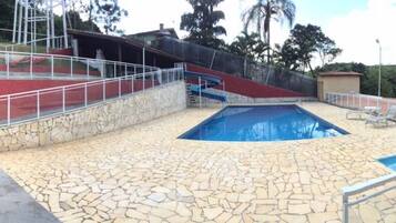 Relax by the pool surrounded by a low wall and metal railing.