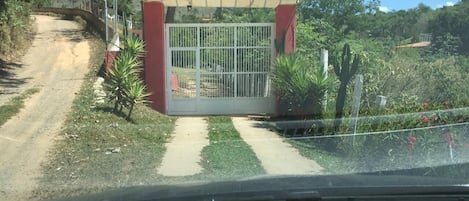 A gated entrance with a metal gate, a concrete path, and surrounding greenery.