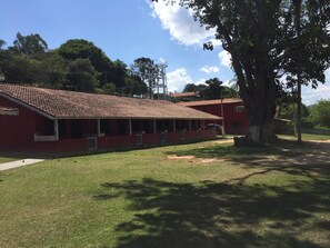 Un bâtiment rouge avec un toit en tuiles, une pelouse verdoyante et un grand arbre.