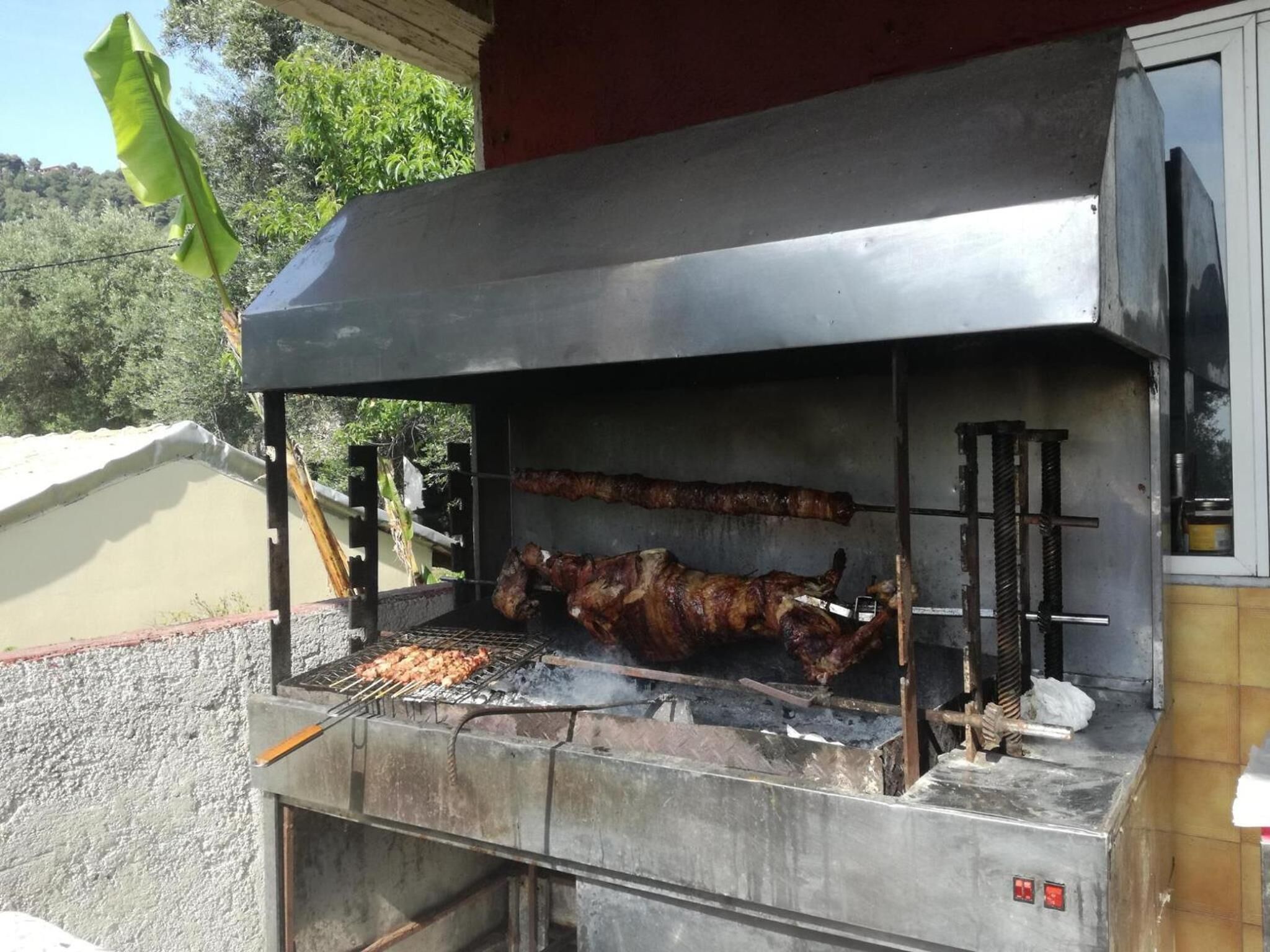 Una parrilla grande para exteriores con múltiples superficies de cocción y una chimenea, presumiblemente utilizada para hacer parrilladas.