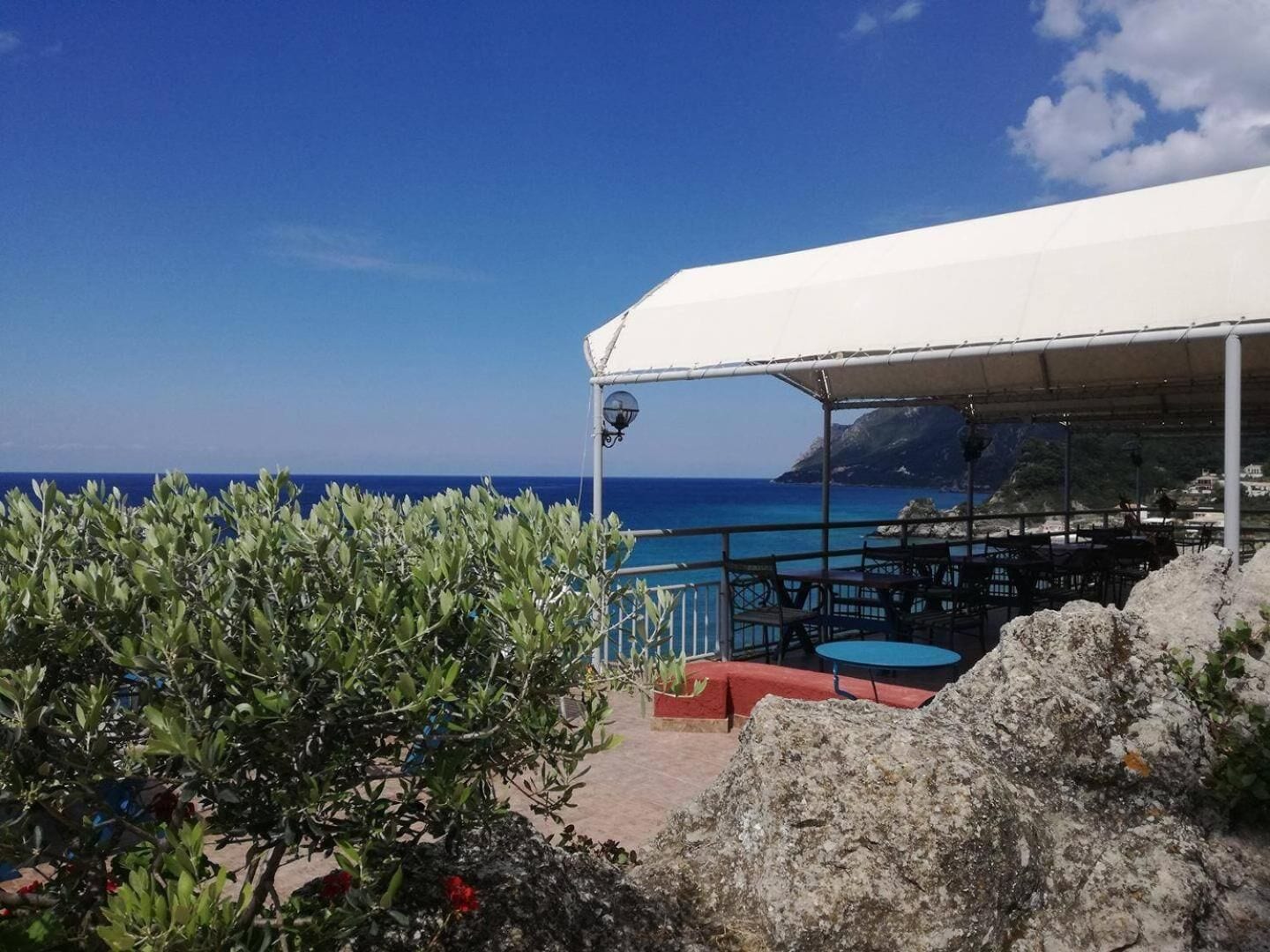 Un restaurante frente al mar con terraza, una marquesina blanca y vistas al océano.