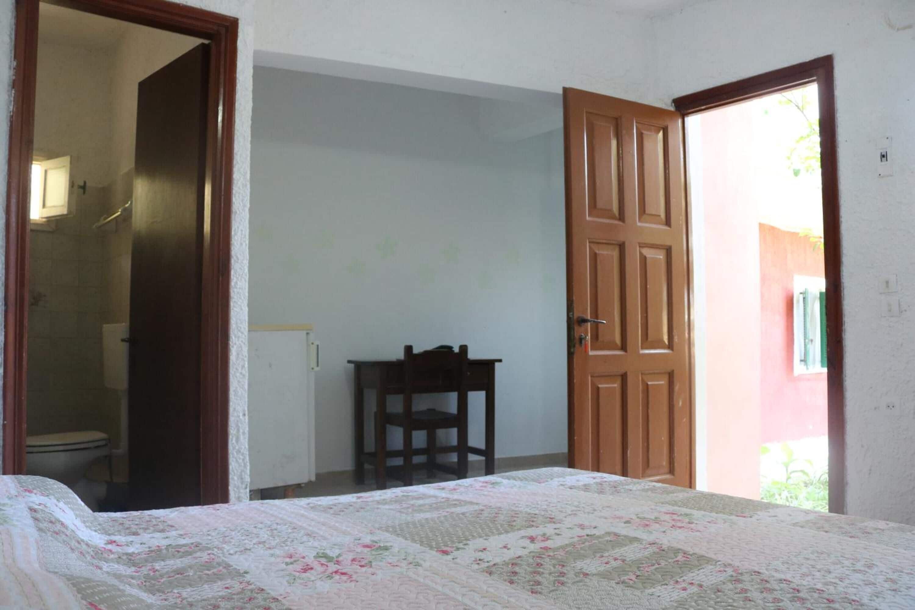 A bedroom with a bed, a chair, and an open door leading to a bathroom.