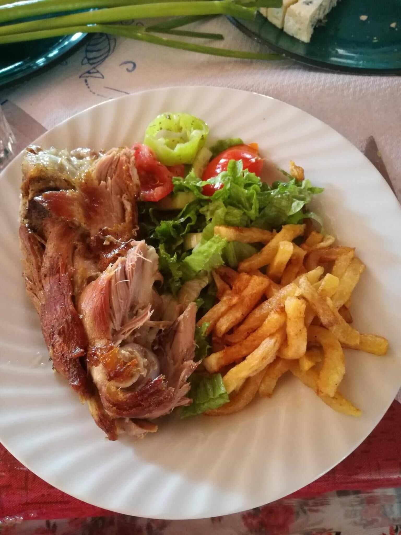 A plate with a piece of meat, lettuce, cherry tomatoes, and French fries.