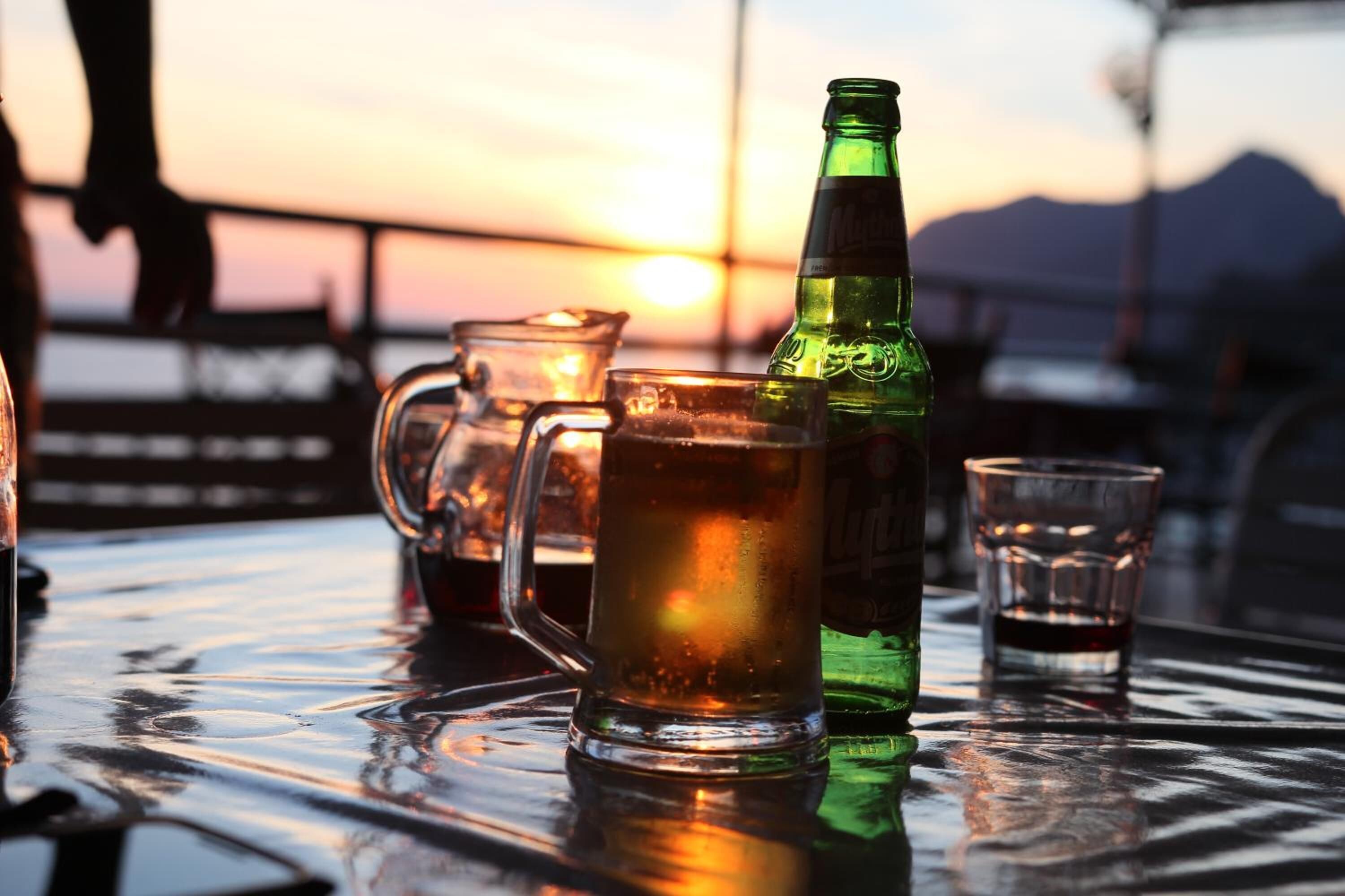 A table with a green bottle, a glass pitcher, and a glass.