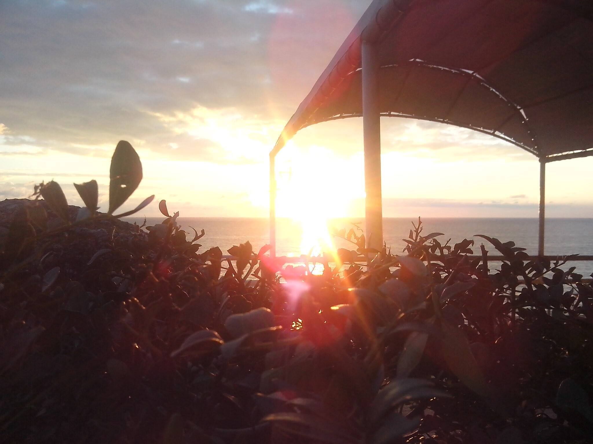 Vista al atardecer desde un espacio exterior techado con vista al mar.