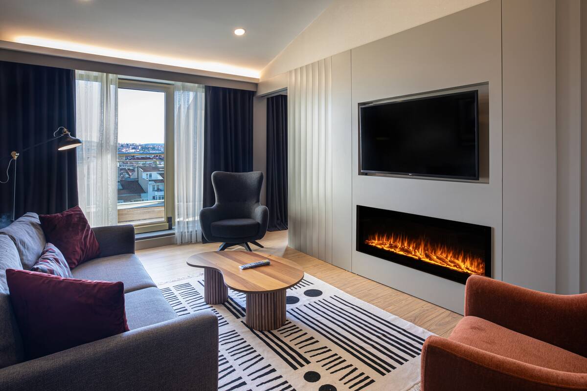 Een moderne woonkamer met een bank, fauteuil en een flatscreen televisie aan de muur.