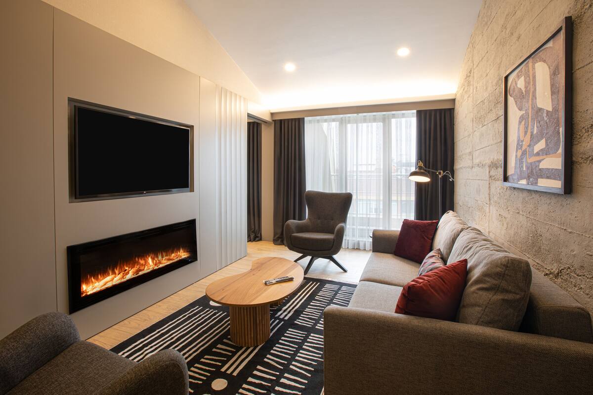 Een moderne woonkamer met een flatscreen televisie, een open haard, een bank, een fauteuil en een salontafel.
