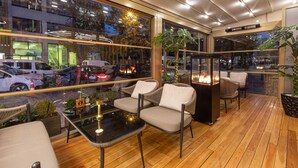 Un espace de détente intérieur moderne, doté d’un plancher en bois, de murs en verre et offrant une vue sur la rue.