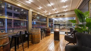 Un intérieur moderne avec un plancher en bois, des tabourets de bar et de grandes fenêtres donnant sur la rue.