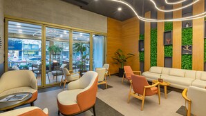 Un hall d’entrée moderne avec un canapé, des fauteuils, une table basse et une grande fenêtre donnant sur la ville.