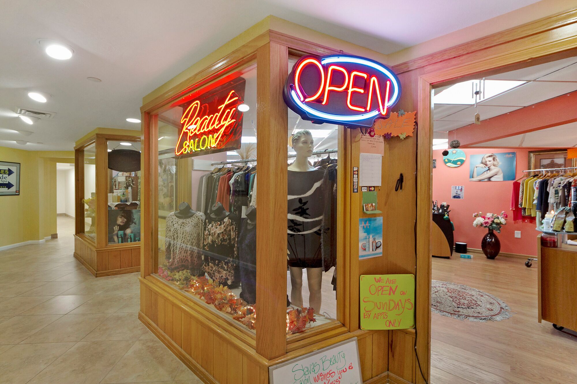 A salon with a neon 'OPEN' sign, a mannequin in a dress, and a sign stating 'We are open on Sundays by appointment only'.