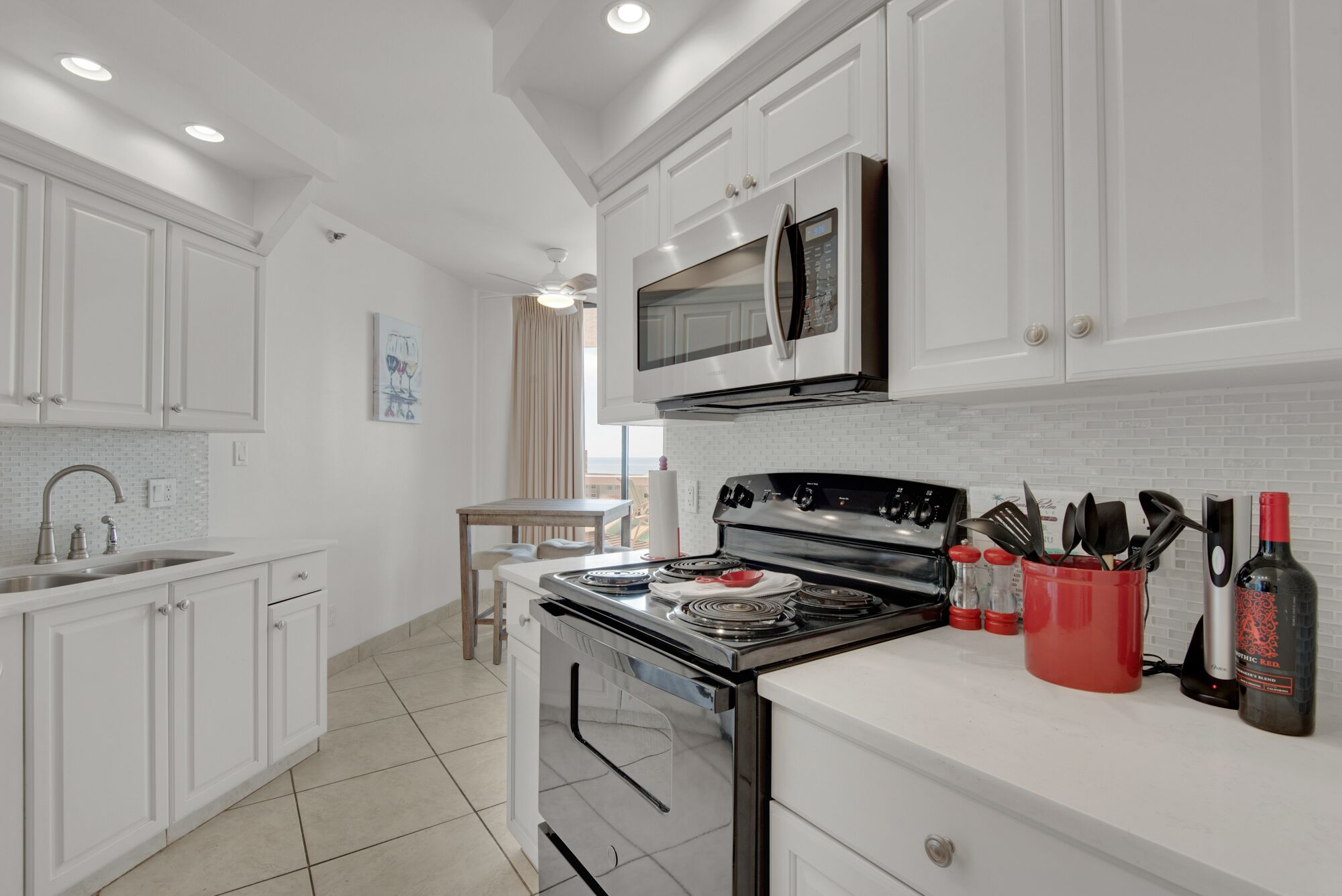 A modern kitchen with white cabinetry, a stainless steel stove, and a microwave above the counter.
