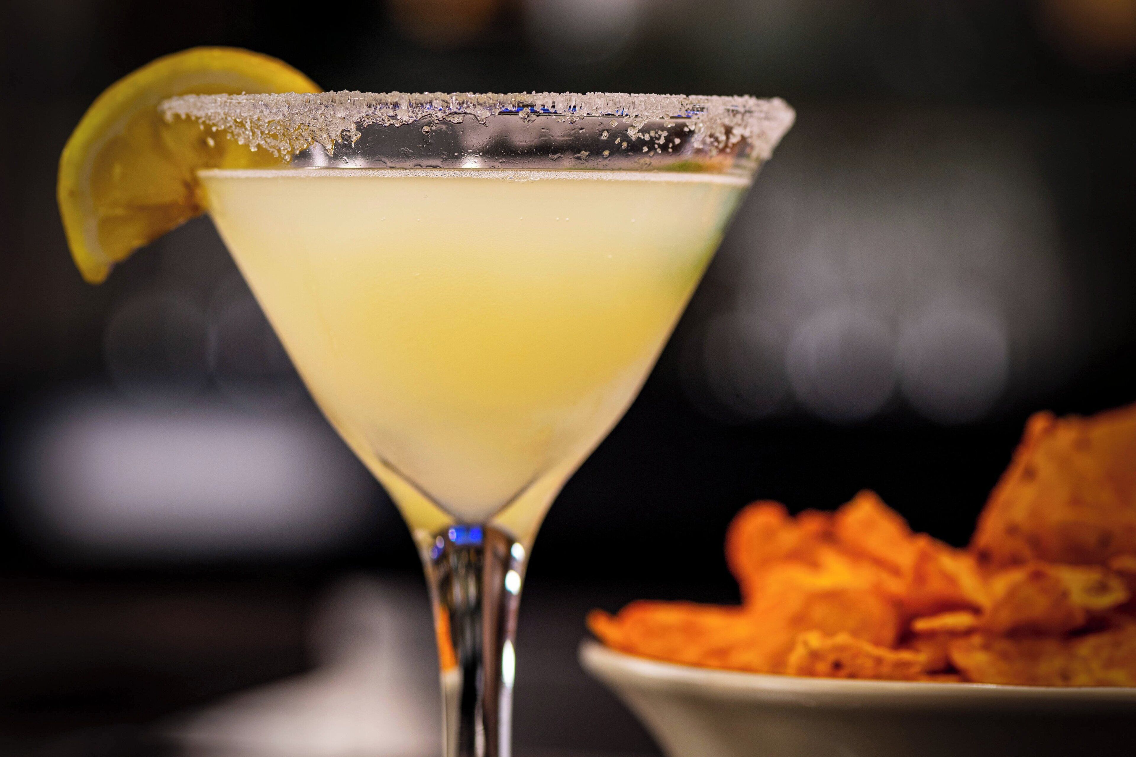A cocktail with a salted rim and a lemon garnish, served in a martini glass.