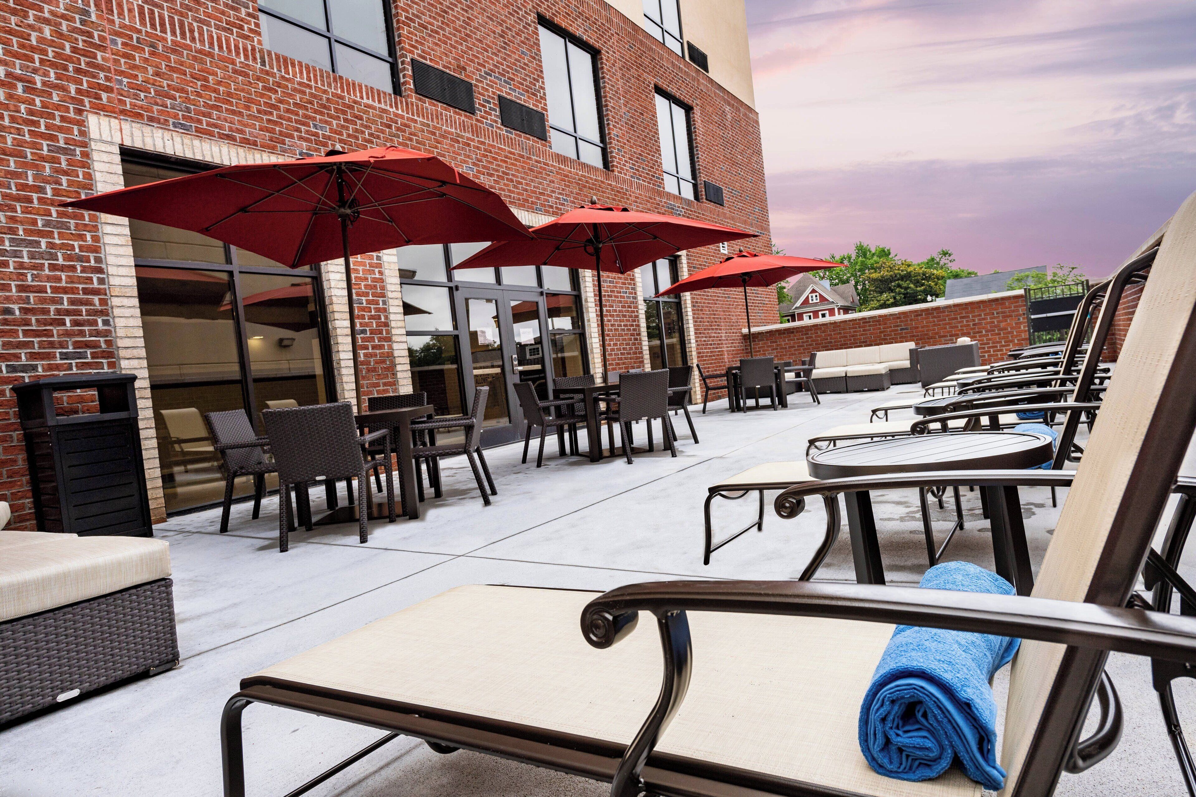 An outdoor patio area with brick walls, outdoor seating, and red umbrellas.