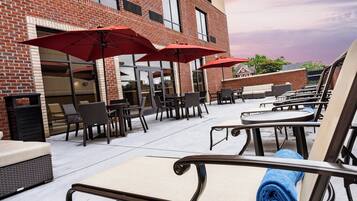 An outdoor patio area with brick walls, outdoor seating, and red umbrellas.