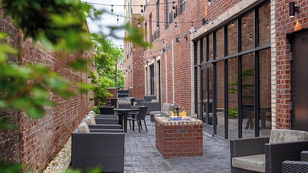 An outdoor patio with brick walls, wicker furniture, and a fire feature. - Courtyard by Marriott Winston - Salem Downtown (Winston-Salem)
