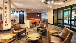 A modern bistro with leather chairs, a glass table, and pendant lighting. - Courtyard by Marriott Winston - Salem Downtown (Winston-Salem)