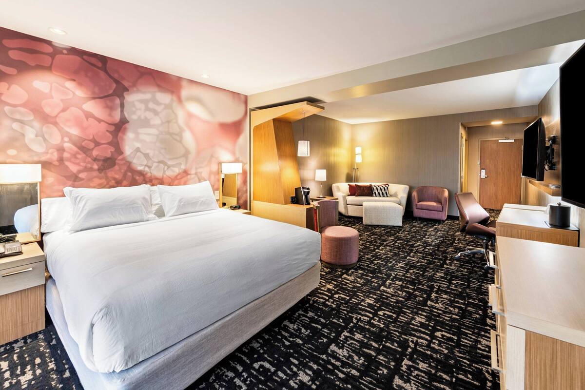 Une chambre d’hôtel avec un grand lit, un bureau, une chaise, un canapé et une télévision.