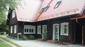 A traditional wooden house with a red tiled roof, a cobblestone driveway, and a small garden area. - Haus Lutki (Burg (Spreewald))