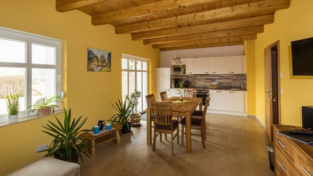 A spacious kitchen with wooden cabinets and a dining area with a wooden table and chairs. - Haus Lutki (Burg (Spreewald))
