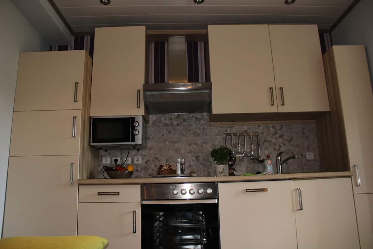 A compact kitchen with a microwave, oven, and stainless steel range hood.