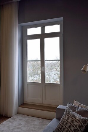 A room with a large window, a sofa, and a lamp. - Mayor's Apartments (Porto)