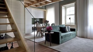 Ett modernt vardagsrum med en trappa, en grön soffa och en matplats i bakgrunden.