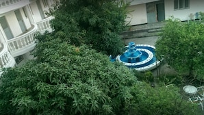 Un immeuble à plusieurs étages doté de balcons, d’une fontaine et d’une végétation luxuriante.