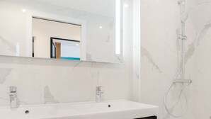 A bathroom with a white sink, two faucets, a mirror, and a shower. - Hedonist House - Design Loft Design in  Heart of Paris ! (Paris)