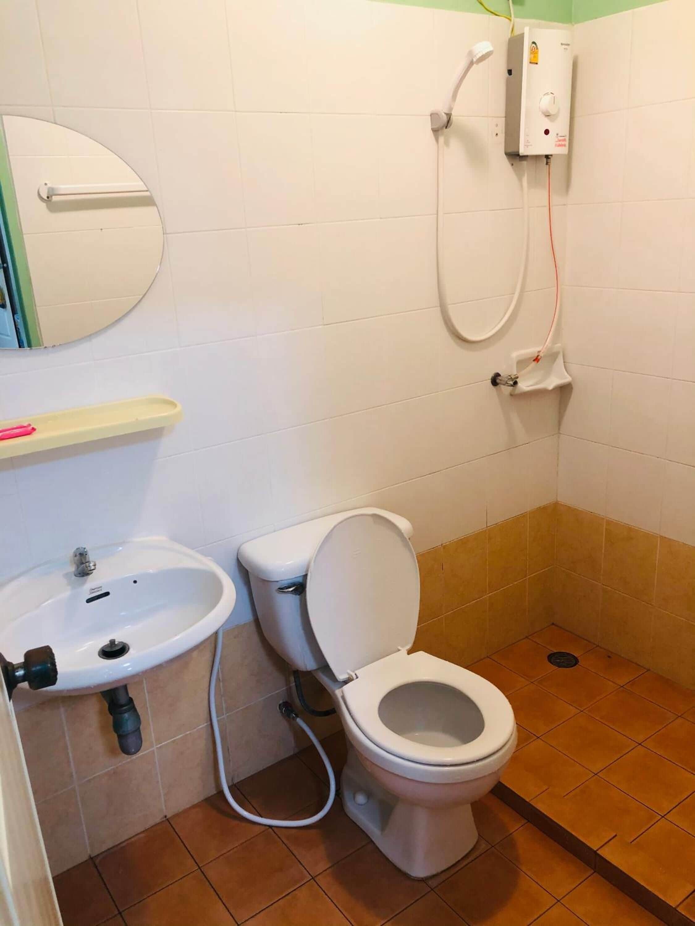 A small bathroom with a toilet, sink, and a shower unit.