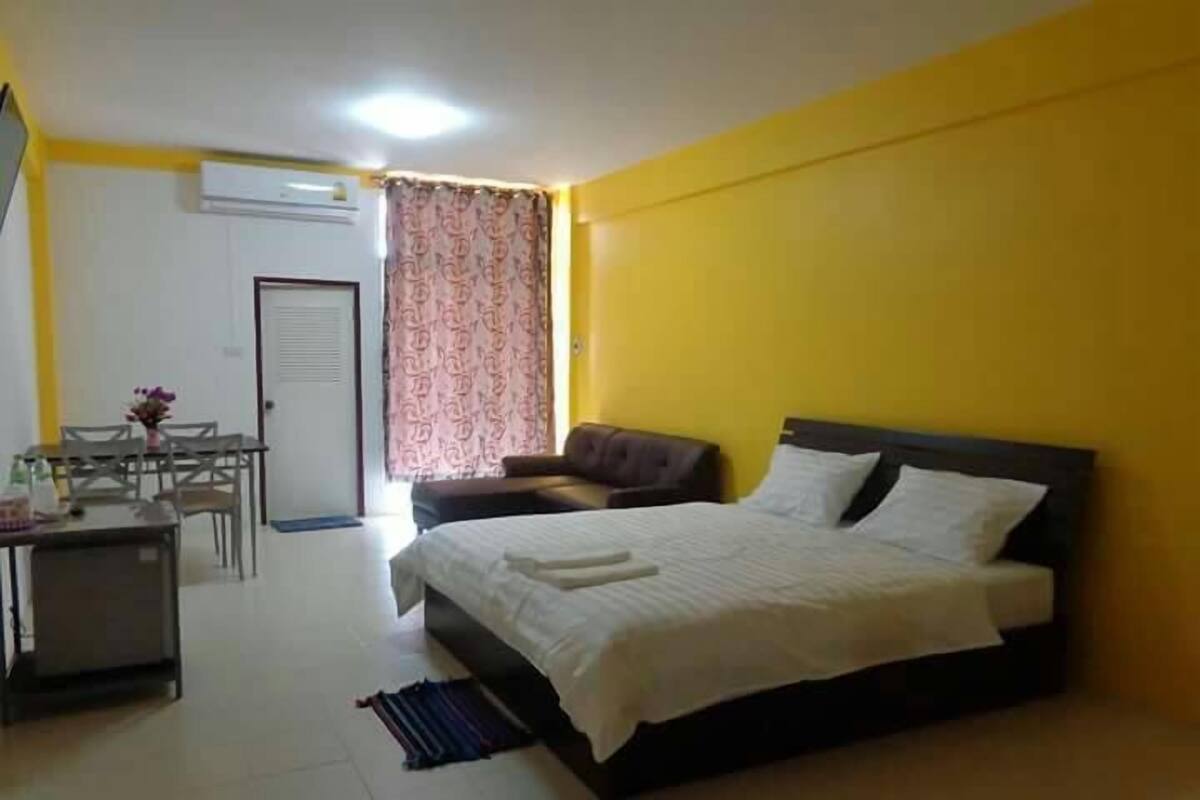 Una habitación con cama, escritorio, silla y ventana con cortinas.
