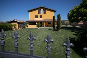 A two-story yellow house with a tiled roof, a well-maintained lawn, and a decorative fence in the foreground. - B&B La Canfora (Atri)