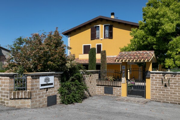 A yellow building with a stone wall entrance, a sign reading "La Cantina," and a tiled roof. - B&B La Canfora (Atri)