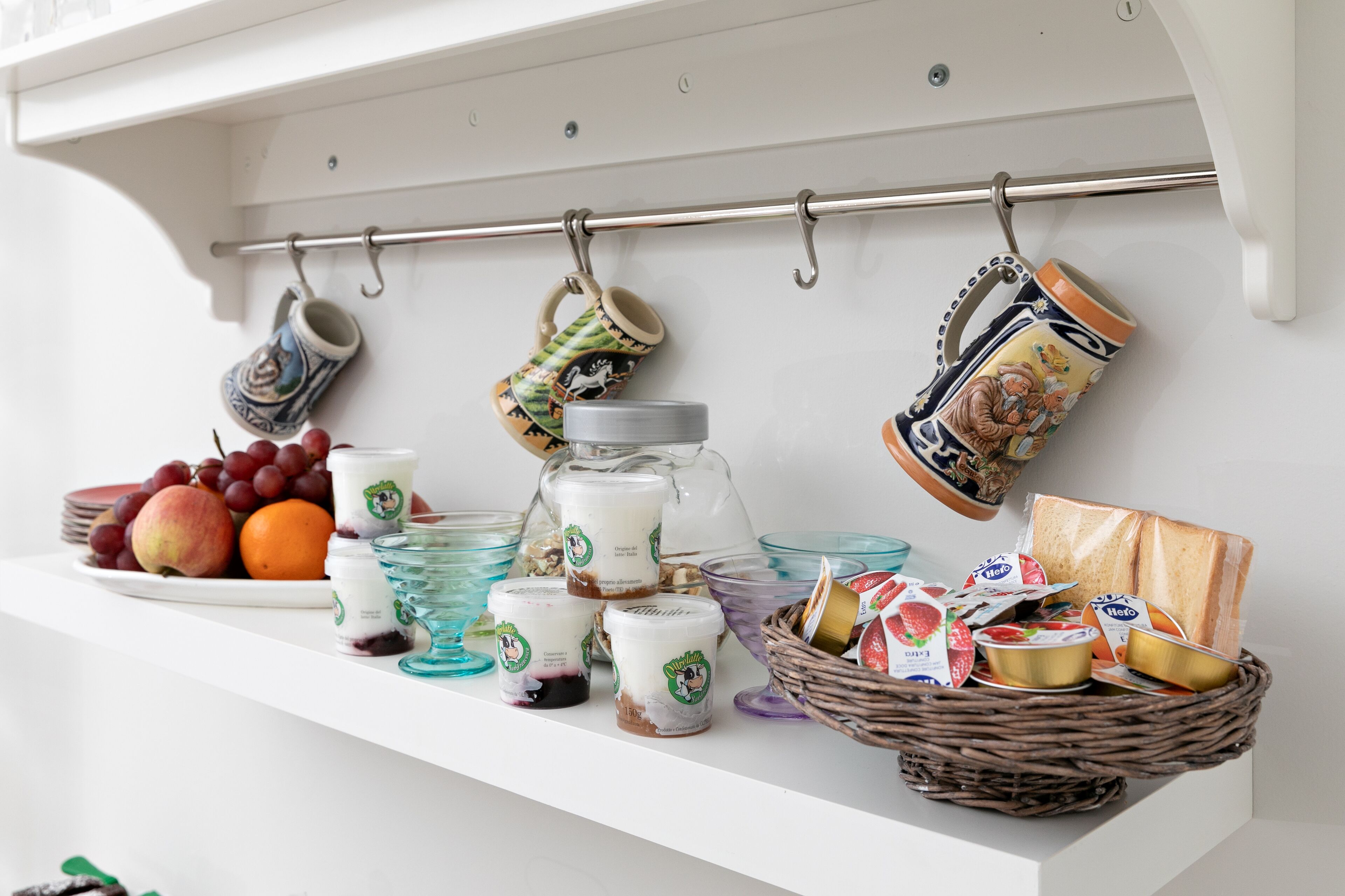 Een plank met verschillende etenswaren, waaronder fruit, yoghurt en brood.