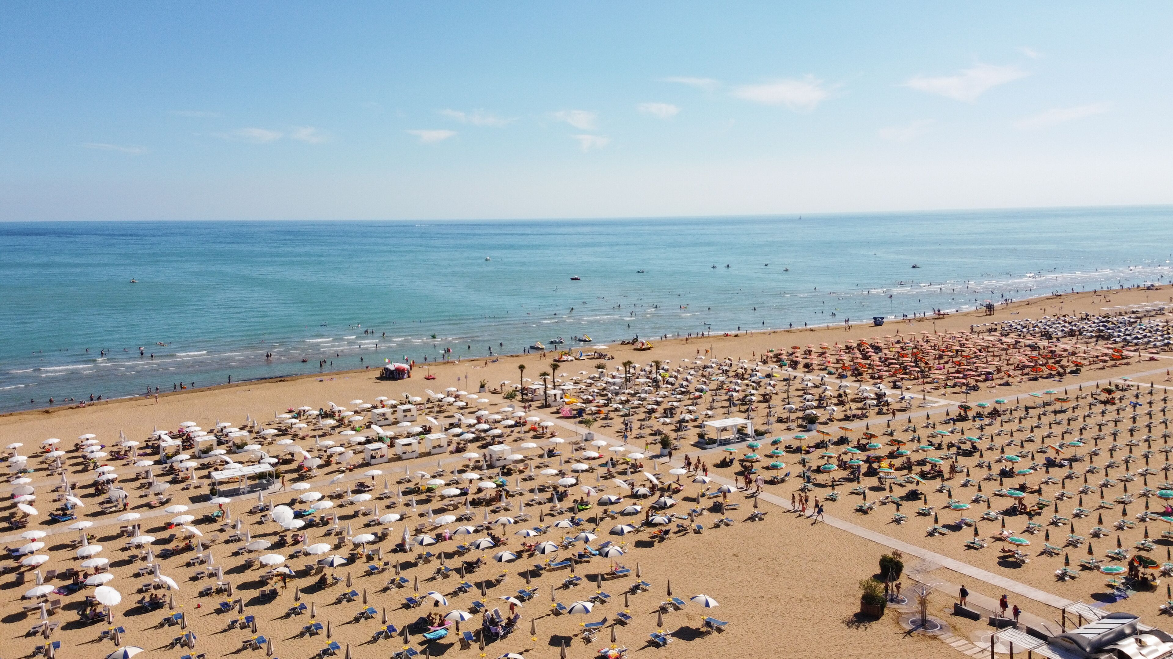 A beach with numerous umbrellas and sun loungers arranged in rows.