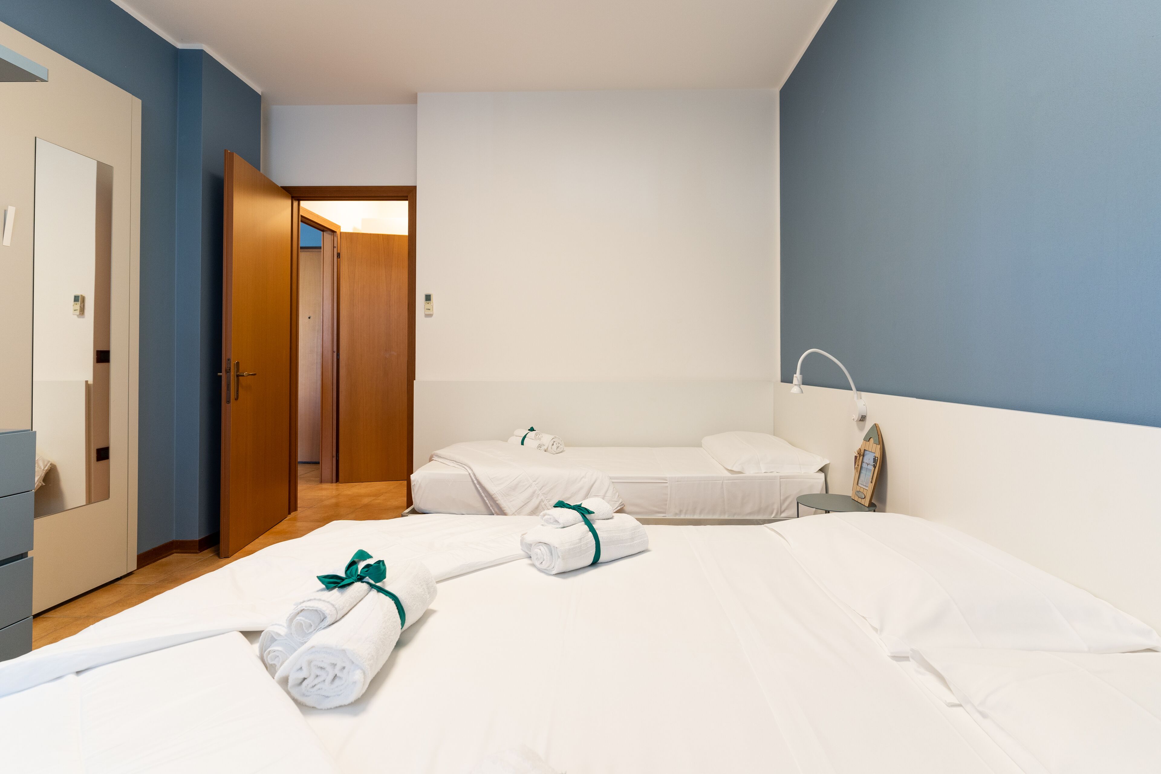 Een hotelkamer met twee bedden, een badkamer en een deur naar een andere kamer.