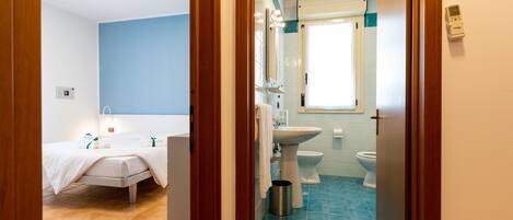 A hotel bathroom with a bed, sink, and toilet.