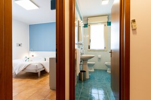 Casa de banho de hotel com cama, lavatório e sanita.
