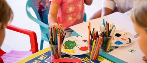 A group of children engaged in a painting activity with various art supplies on a table.