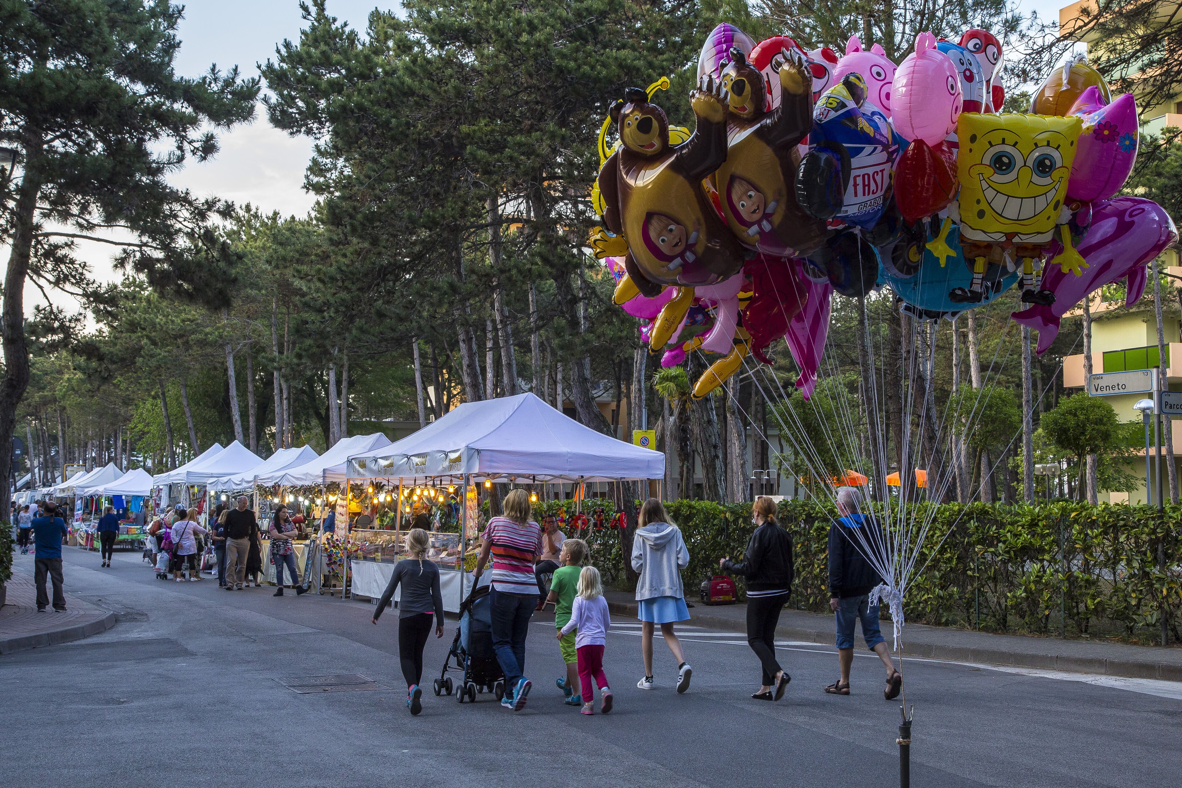 A street lined with tents and people walking.