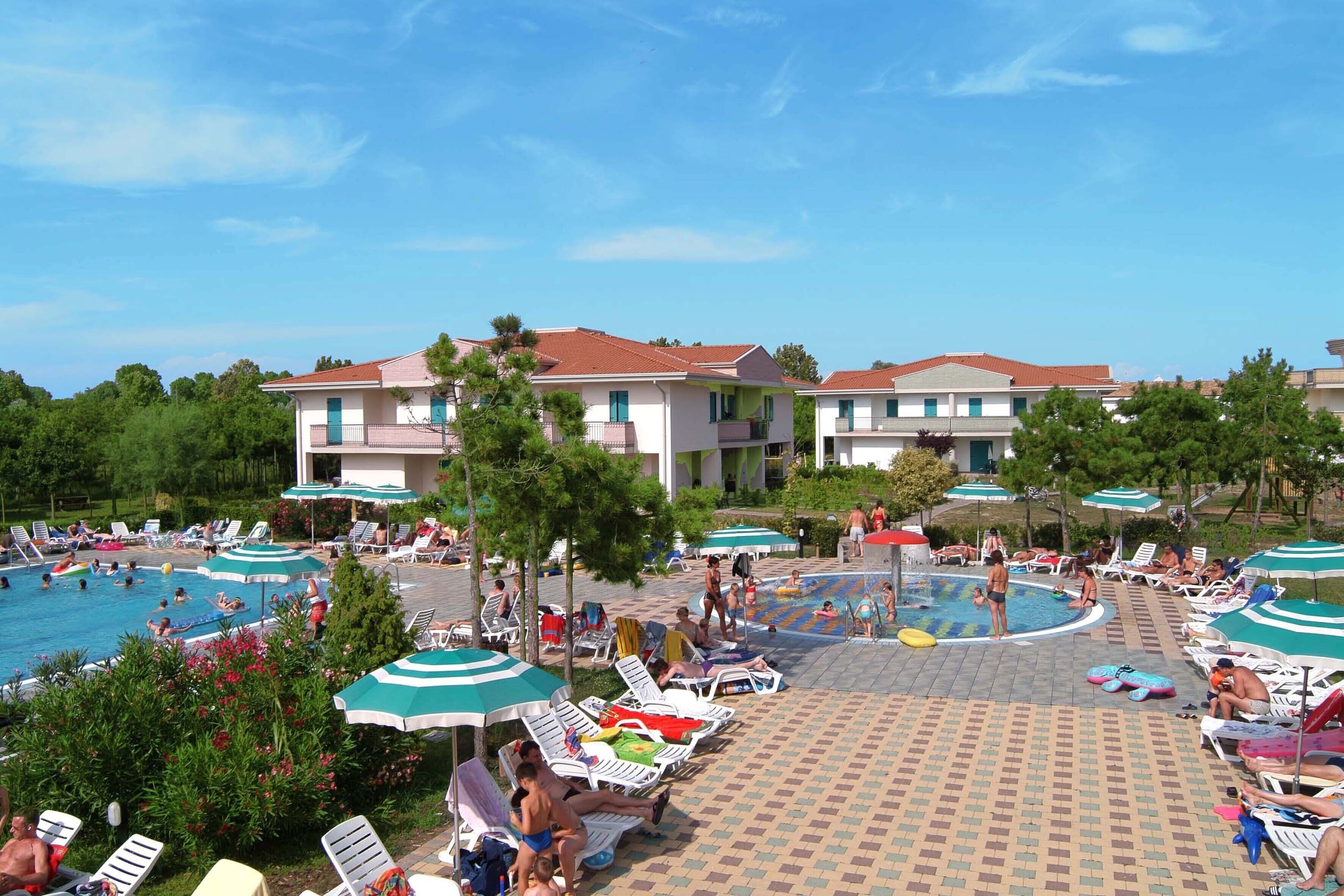 Un complejo turístico con varias piscinas, tumbonas y sombrillas.