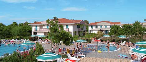 Un complejo turístico con varias piscinas, tumbonas y sombrillas.